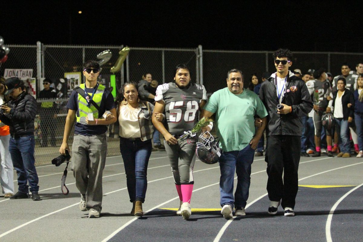 Eduardo Rojas walks on the track with his family before beating Lindsay on Senior Night on Oct. 25 at Jacob Rankin Stadium.