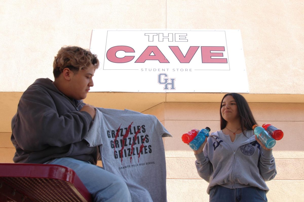 ASB members Alex Vargas and Kendall Miller show students some of the items they can buy in The Cave student store.