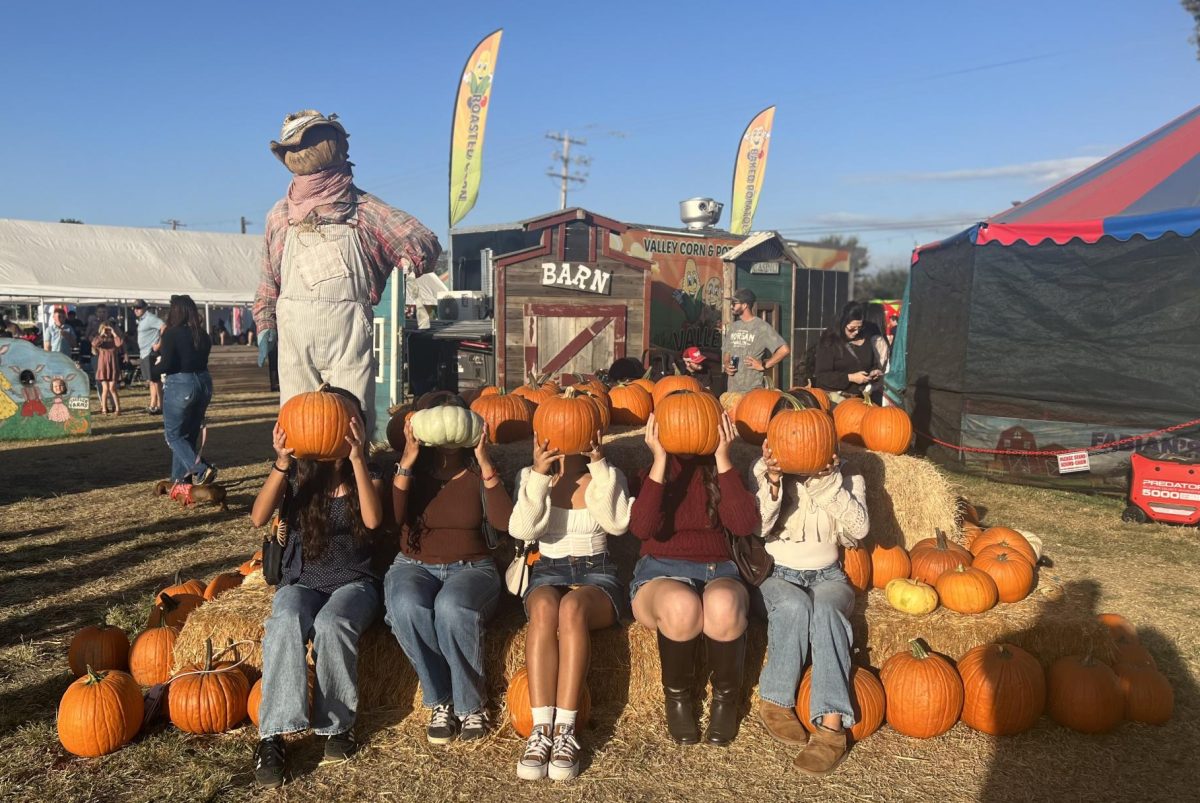 Students take time to pose for a picture at a pumpkin patch.